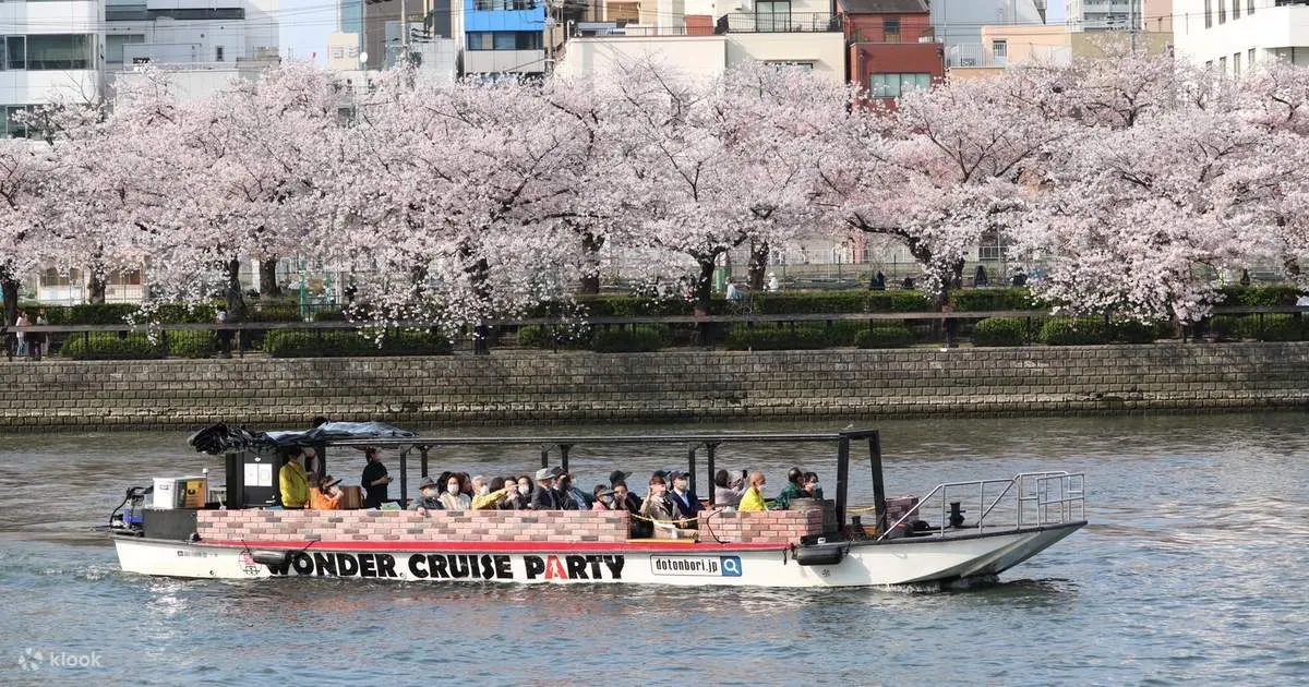 Wonder Cruise boat gliding past thousands of cherry blossom trees lining the Okawa River on an Osaka river cruise in spring